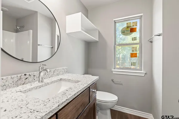 a bathroom with a granite countertop sink a toilet and a mirror