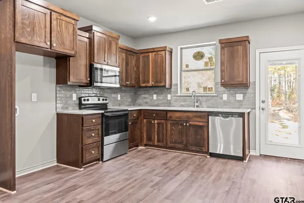 a kitchen with stainless steel appliances granite countertop a stove a sink and a microwave
