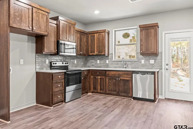 a kitchen with stainless steel appliances granite countertop a stove a sink and a microwave