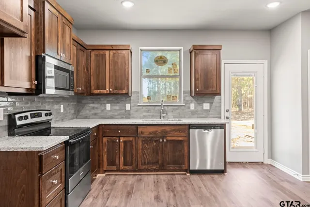 a kitchen with stainless steel appliances granite countertop wooden cabinets stove top oven and sink