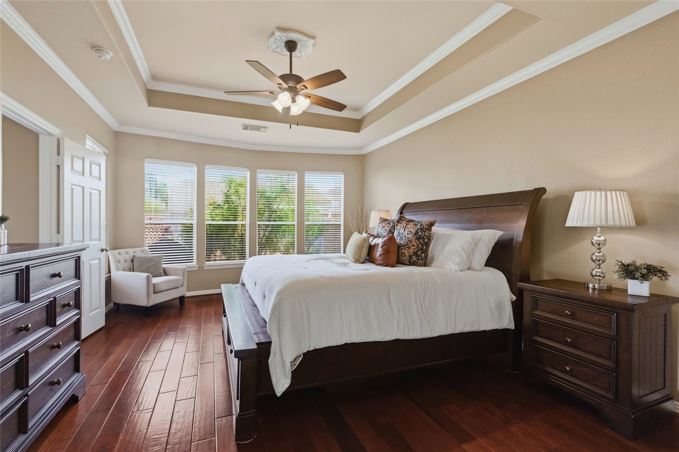 20722 Windrose Bend Drive Spring, TX 77379 - Photo 20 of 50 Discover tranquility in your spacious primary bedroom, featuring elegant tray ceilings, rich wood flooring, and abundant natural light streaming through expansive windows.