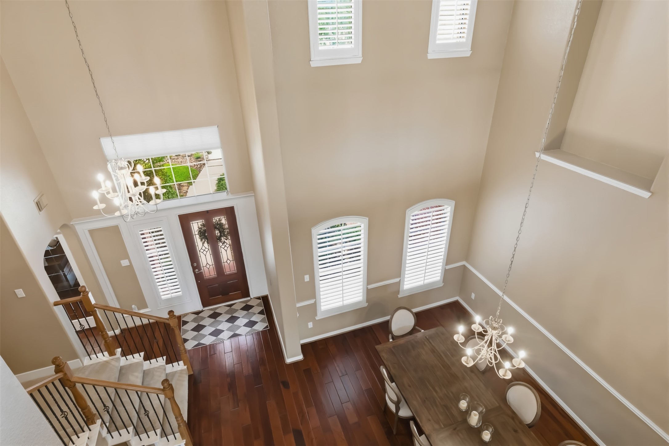 20722 Windrose Bend Drive Spring, TX 77379 - Photo 31 of 50 This photo showcases your spacious, elegant entryway, dining area with soaring high ceilings, and features the hardwood floors, grand staircase, and large windows with plantation shutters. The chandeliers add a touch of sophistication & design.