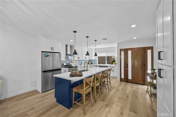 a kitchen with a refrigerator a stove and a dining table with wooden floor