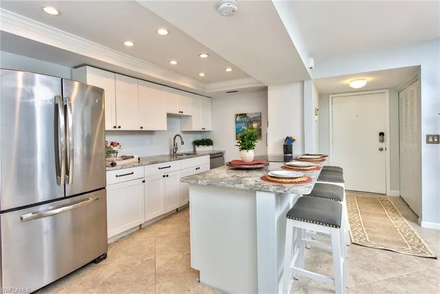 a kitchen with stainless steel appliances granite countertop a refrigerator a sink dishwasher a stove and white cabinets with wooden floor