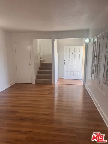 a view of an empty room with wooden floor and stairs