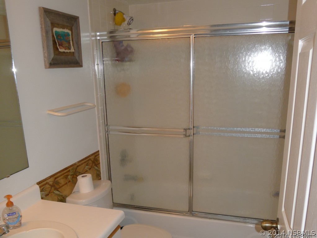 6544 Engram Road, Unit E204 New Smyrna Beach, FL 32169 - Photo 13 of 22 a bathroom with a glass shower door