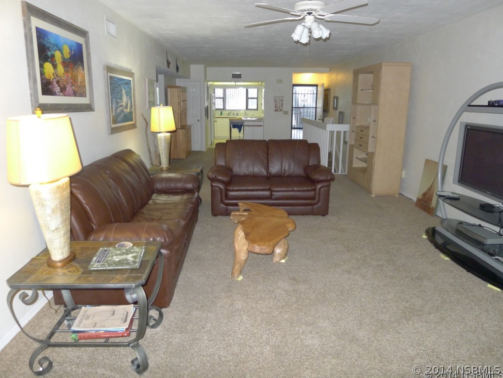 6544 Engram Road, Unit E204 New Smyrna Beach, FL 32169 - Photo 17 of 22 a living room with furniture a chandelier and a flat screen tv