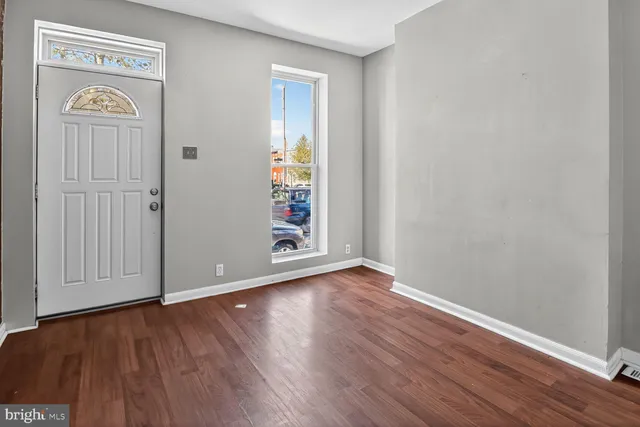 a view of an empty room with wooden floor and a window