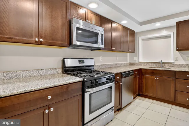 a kitchen with granite countertop stainless steel appliances a sink dishwasher a stove top oven and cabinets