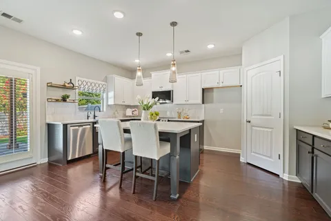 a kitchen with a dining table chairs wooden floor cabinets and stainless steel appliances