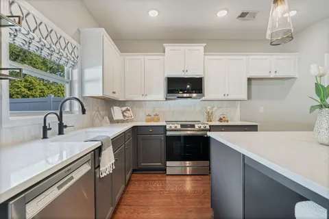 a kitchen with stainless steel appliances granite countertop a sink dishwasher stove top oven and cabinets with wooden floor