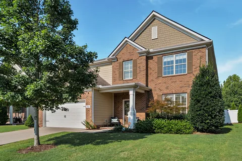 a front view of a house with a yard and trees