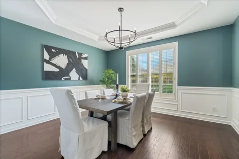 a dining room with furniture a chandelier and wooden floor