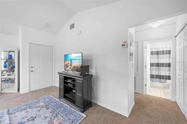 a view of an empty room with kitchen and hallway