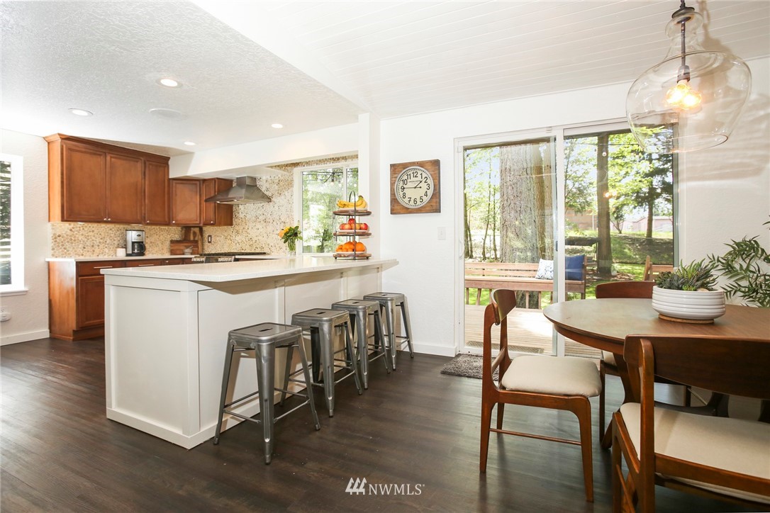 218 221st Street Southwest Bothell, WA 98021 - Photo 9 of 40 a kitchen with stainless steel appliances granite countertop a stove a sink a refrigerator a dining table and chairs with wooden floor