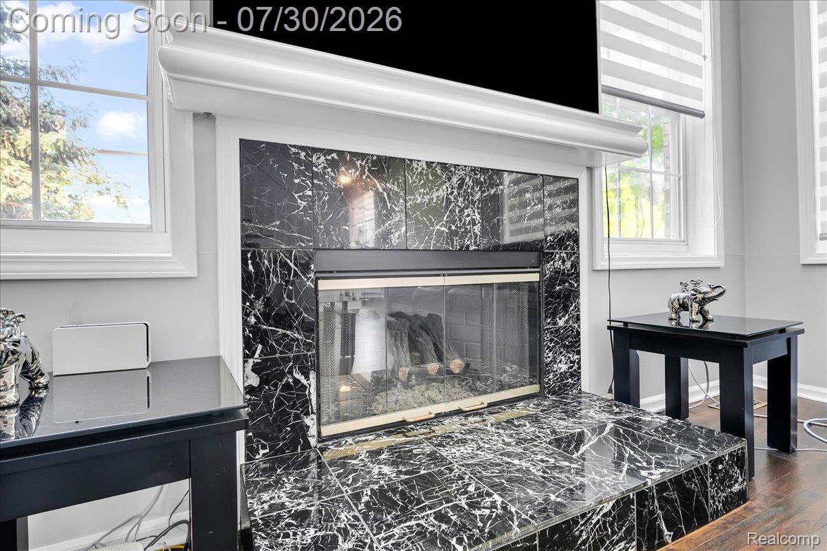 Fireplace featuring a black and white tiled surround and hearth, framed by a white mantel