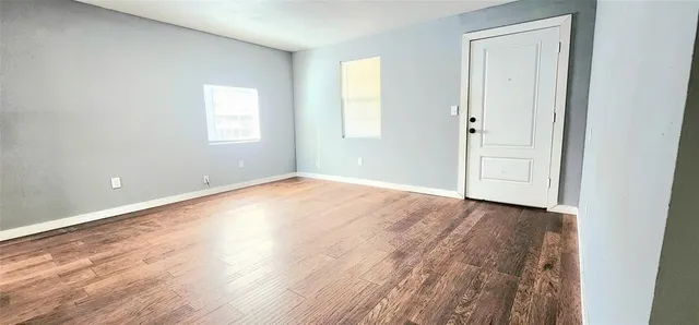 a view of an empty room with wooden floor and a window