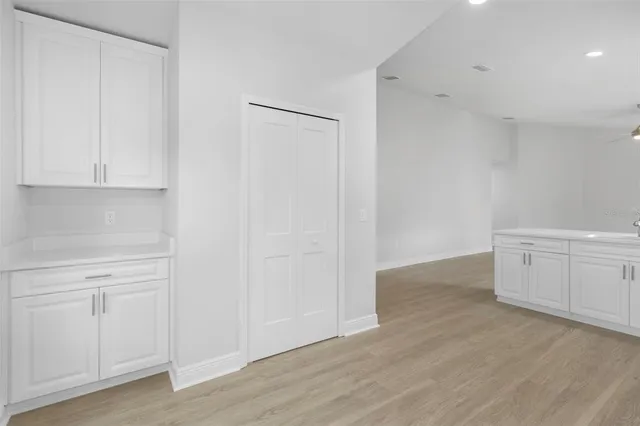 a view of a kitchen with white cabinets and wooden floor