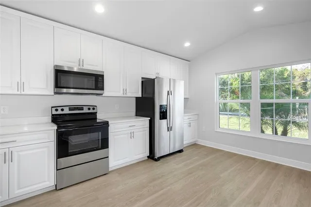 a kitchen with stainless steel appliances a stove top oven a refrigerator and a microwave