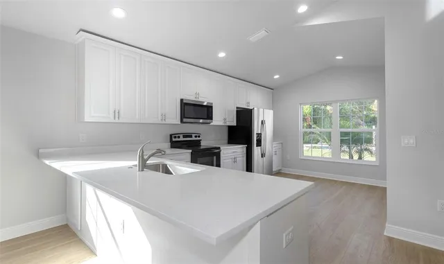 a kitchen with a sink a counter top space appliances and cabinets