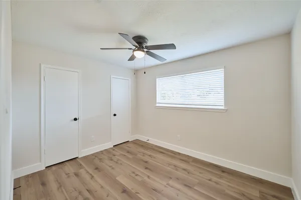 a view of empty room with wooden floor and fan