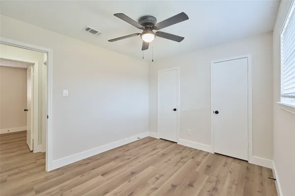 an empty room with wooden floor and ceiling fan
