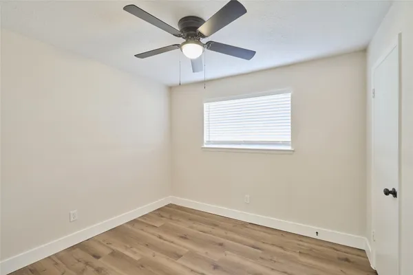an empty room with a window and a fan