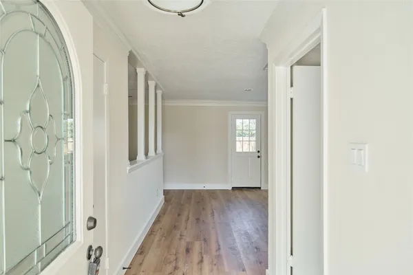 a view of a hallway with wooden floor and a bathroom