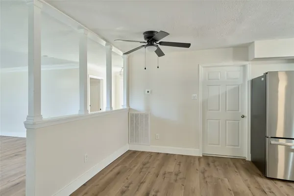 a view of a refrigerator in kitchen and an empty room