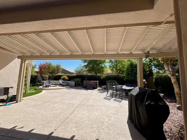a view of a patio with a table and chairs under an umbrella with a tub