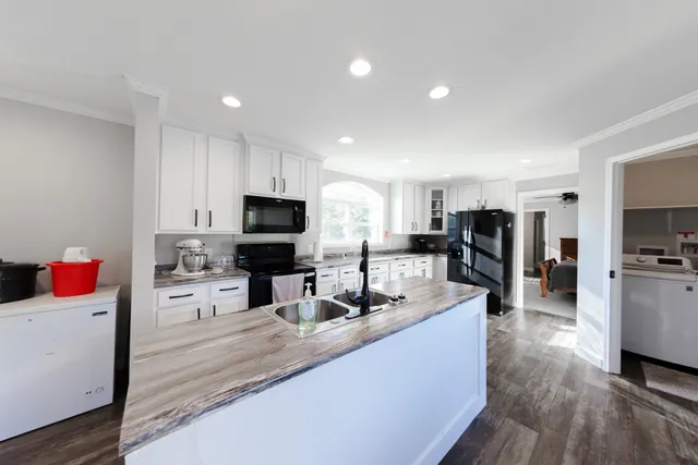 a kitchen with stainless steel appliances kitchen island granite countertop a sink dishwasher stove and refrigerator with wooden floor