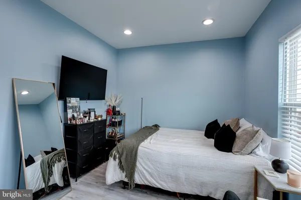 a bedroom with a bed a flat screen tv and a window