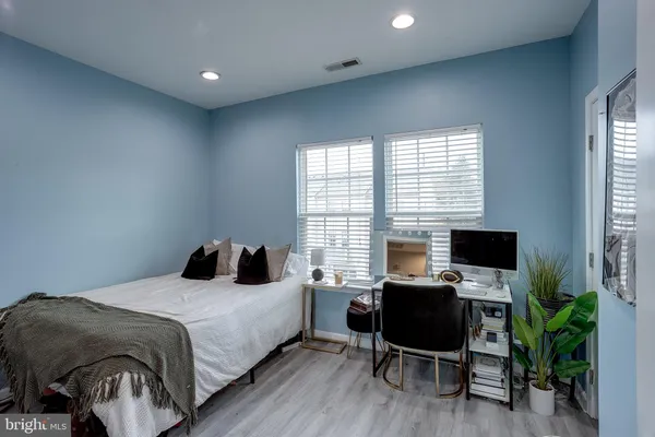 a bedroom with a bed and a computer on a desk next to a window