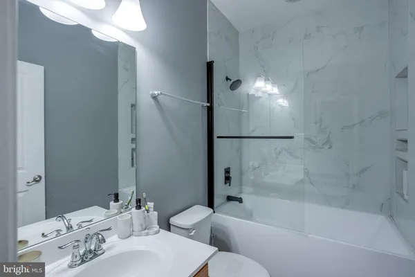 a bathroom with a bathtub shower sink vanity and toilet