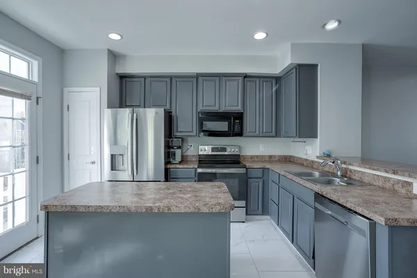 a kitchen with kitchen island granite countertop stainless steel appliances a sink stove refrigerator and a window