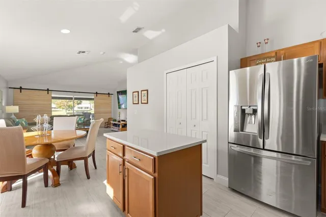 a kitchen with stainless steel appliances a refrigerator a stove a dining table and chairs with wooden floor