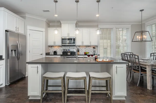 a kitchen with kitchen island granite countertop a table chairs refrigerator and microwave