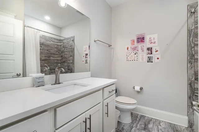a bathroom with a granite countertop sink toilet and a large mirror