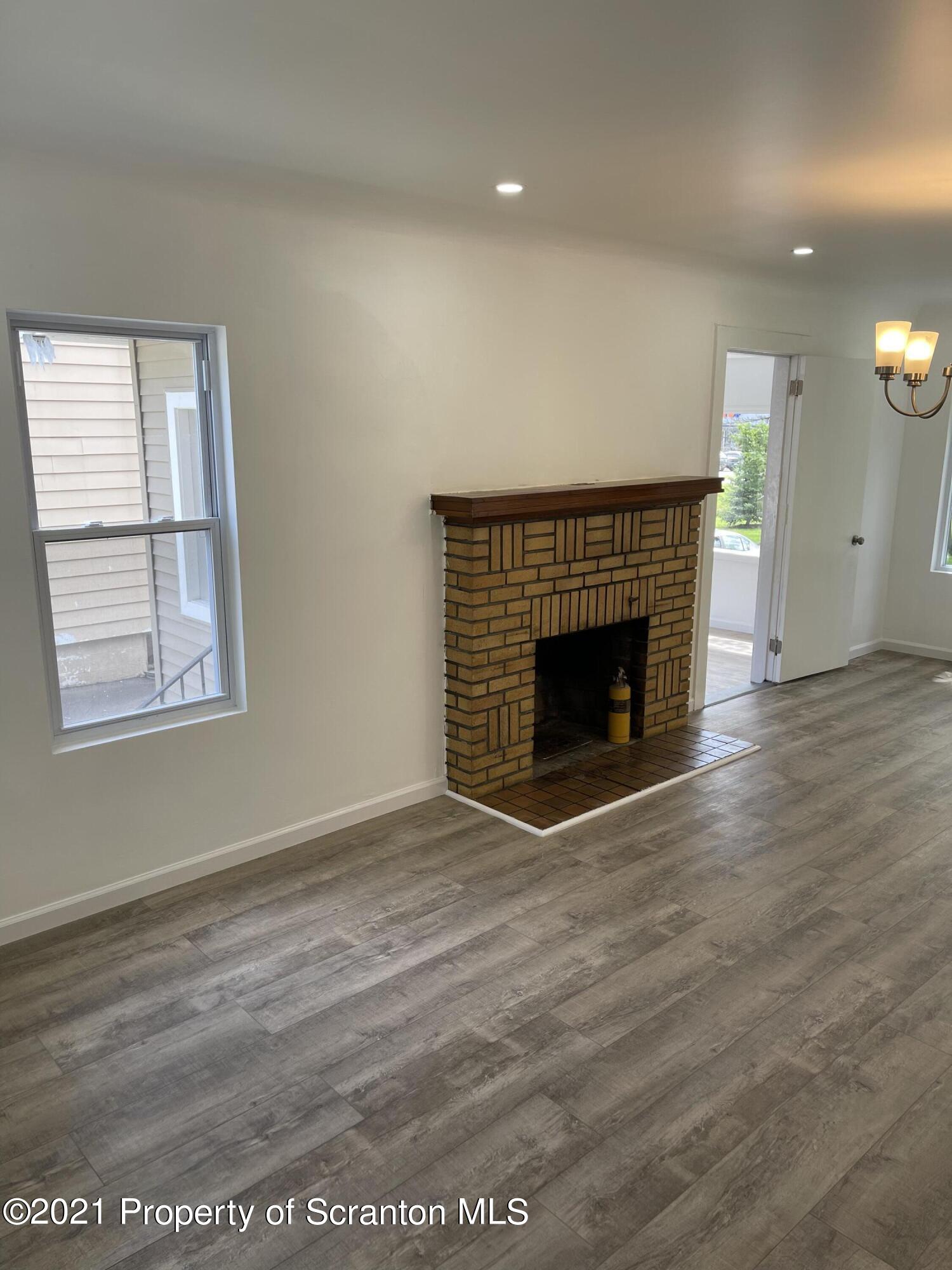 9 Front Street Clarks Summit, PA 18411 - Photo 7 of 22 an empty room with wooden floor fireplace and windows