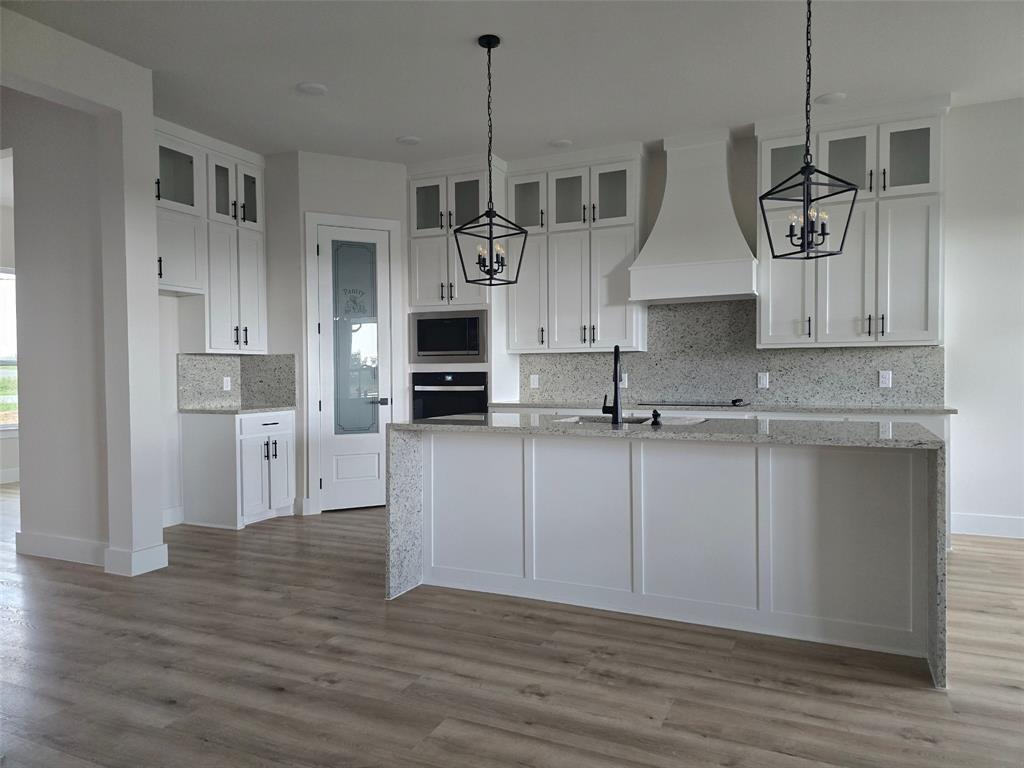 808 N Avenue East Springtown, TX 76082 - Photo 3 of 21 a kitchen with stainless steel appliances granite countertop a sink a microwave a stove and white cabinets with wooden floor