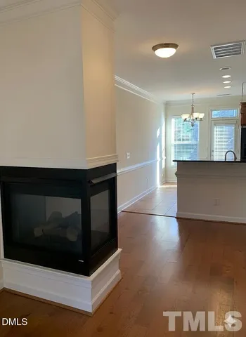 a view of an empty room with kitchen and a fireplace
