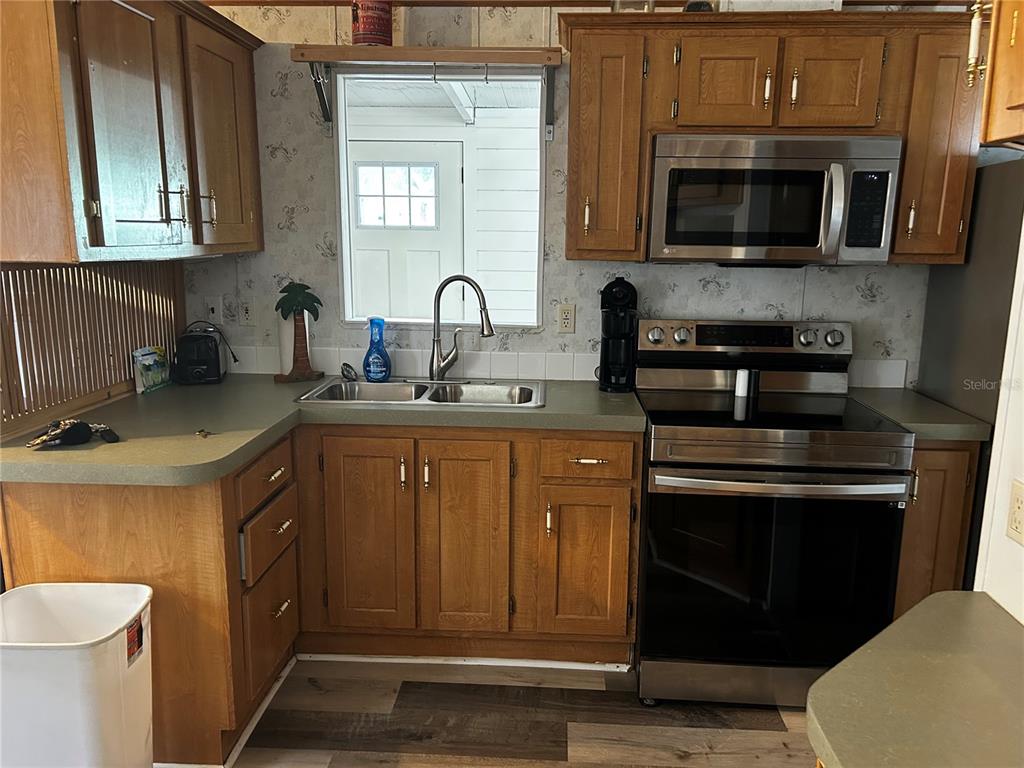 6946 Old Pasco Road, Unit LOT 1 Wesley Chapel, FL 33544 - Photo 7 of 16 a kitchen with sink a microwave a stove and cabinets