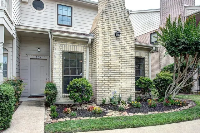 a view of a house with brick walls and a yard with plants