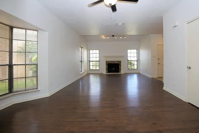 an empty room with wooden floor chandelier and glass door