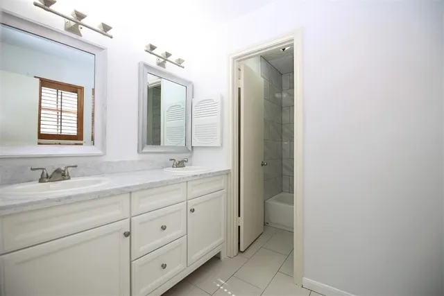 a bathroom with a double vanity sink and mirror with window