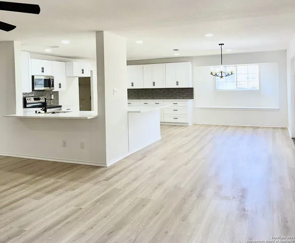 a view of a kitchen with kitchen island a sink wooden floor and a refrigerator