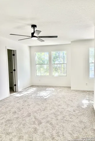 an empty room with a window and a ceiling fan