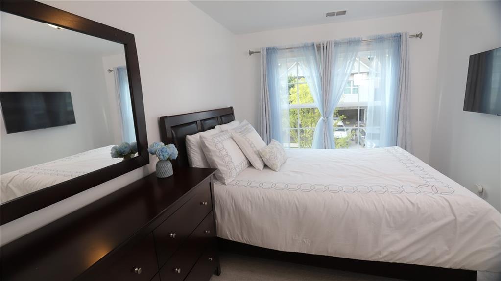 205 Lakeside Place Canton, GA 30114 - Photo 64 of 65 a bedroom with a bed and a flat tv screen on dresser