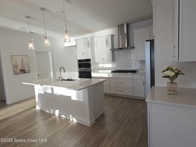 a kitchen with kitchen island granite countertop a sink cabinets and stainless steel appliances