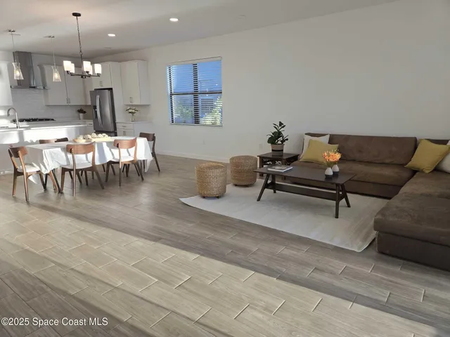 a living room with furniture kitchen view and a chandelier